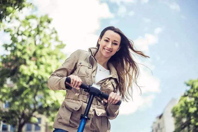 Portrait of smiling woman with E-Scooter