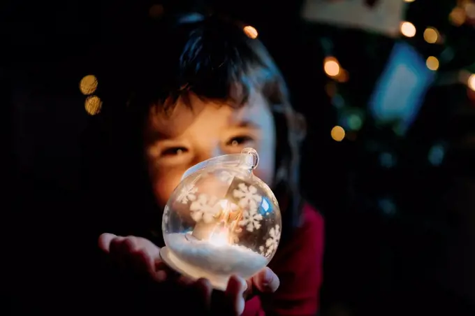Little girl holding lighted glass ball at Christmas time