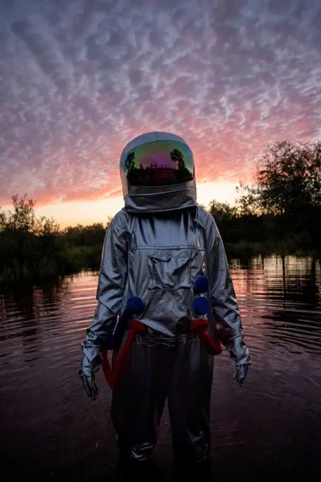 Portrait of spacewoman standing in water at sunset