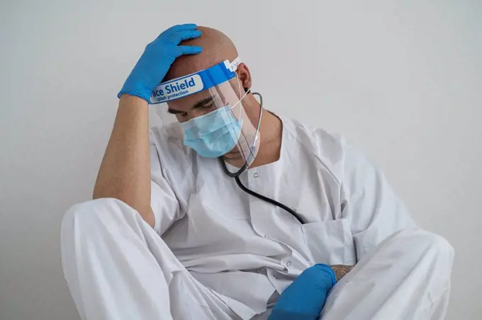 Exhausted man in protective wear sitting on the floor