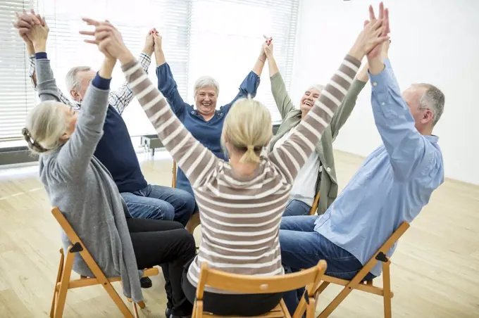 Group of seniors practicing chair gymnastics with instructor in retirement home