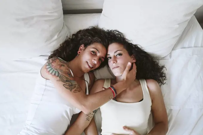 Young lesbian couple relaxing on bed at home