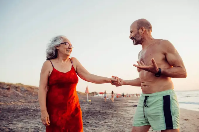 Senior couple holding hands while standing at beach