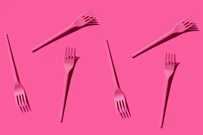 Pattern of pink plastic forks against pink background