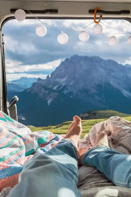 Man relaxing in campervan against mountain range, Sesto Dolomites, Dolomites, Alto Adige, Italy