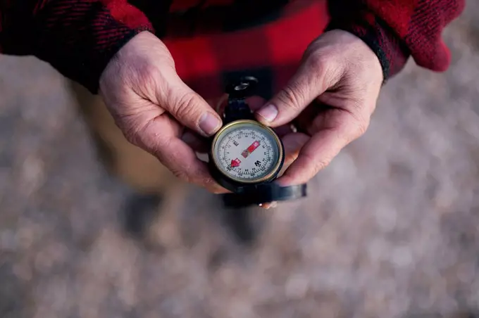 Cropped image of bushcrafter holding navigational compass while hiking