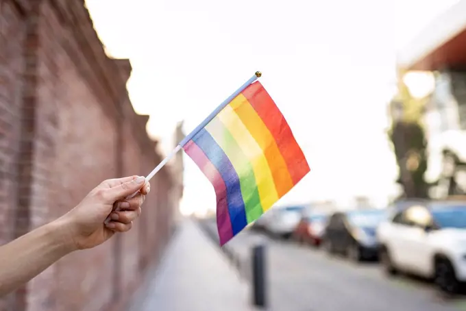 Hand holding LGBTQI rainbow flag