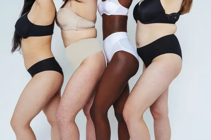 Young women wearing lingerie standing in a line against white background