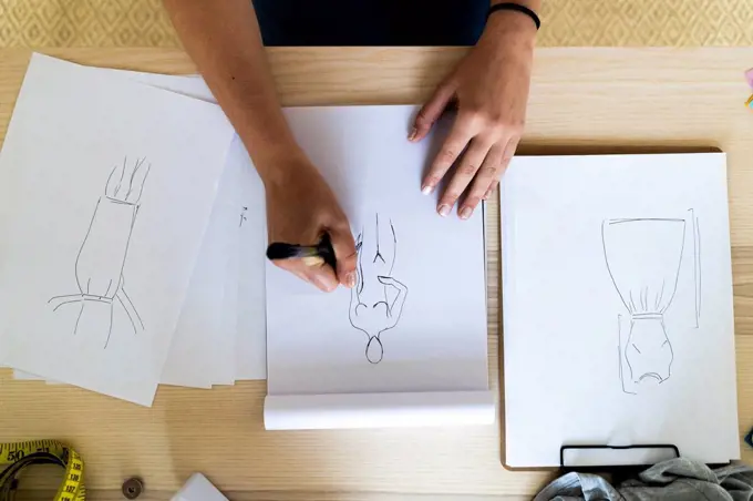 Female designer's hand drawing sketch in book at studio