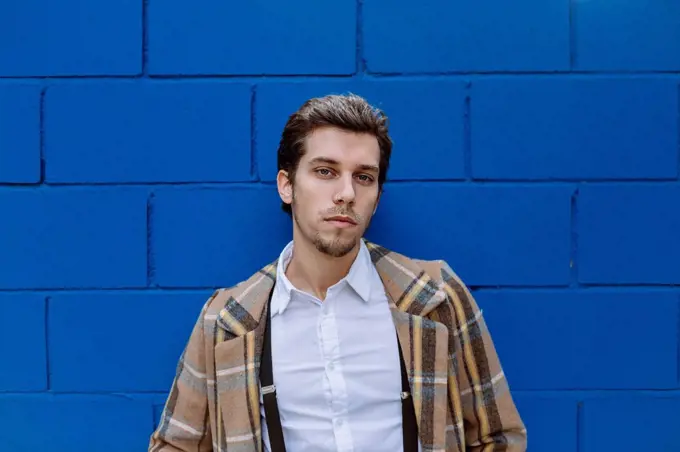 Portrait of stylish man against blue wall