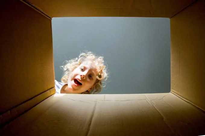 Surprised blond boy looking in cardboard box