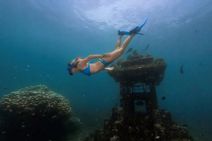 Young woman diving near underwater temple in Java Sea