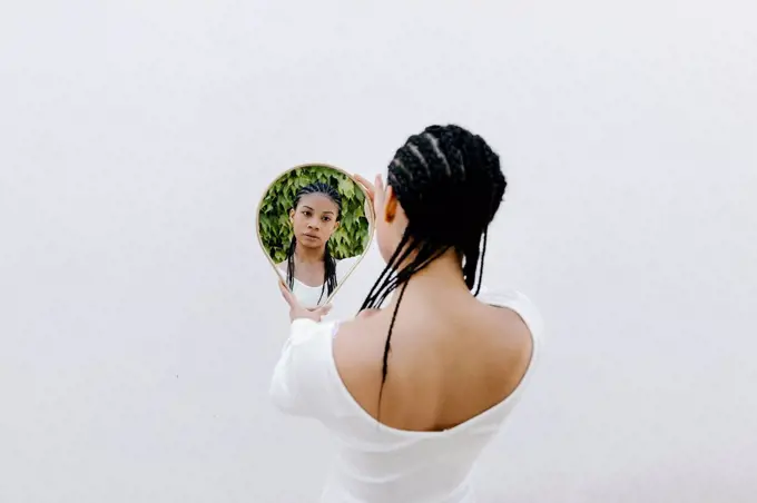 Braided hair woman looking at reflection in mirror