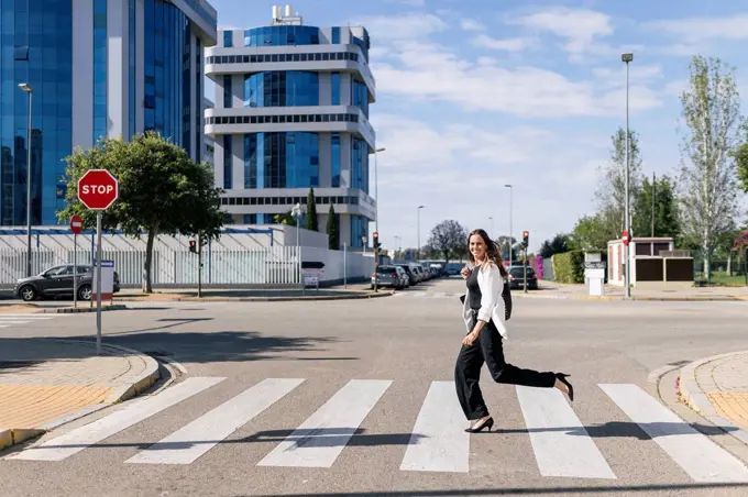 Businesswoman running on road during sunny day