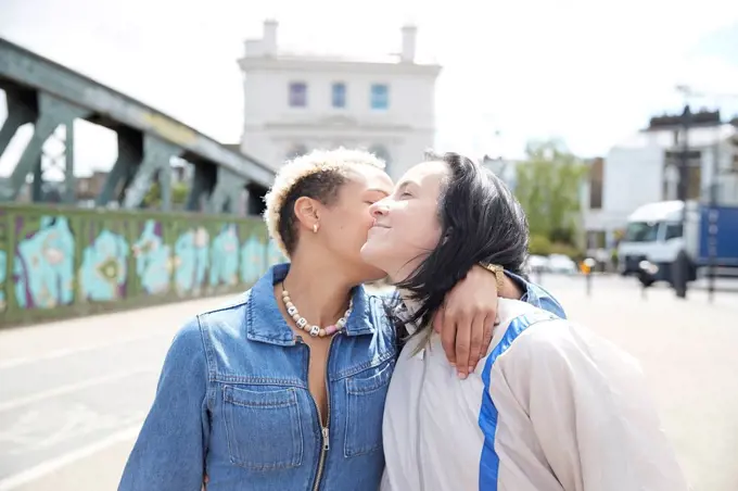 Lesbian woman kissing girlfriend during sunny day
