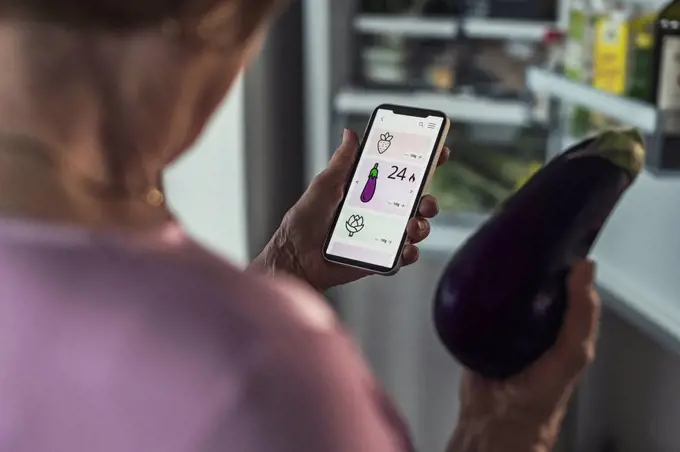 Woman counting calories through smart phone app at home