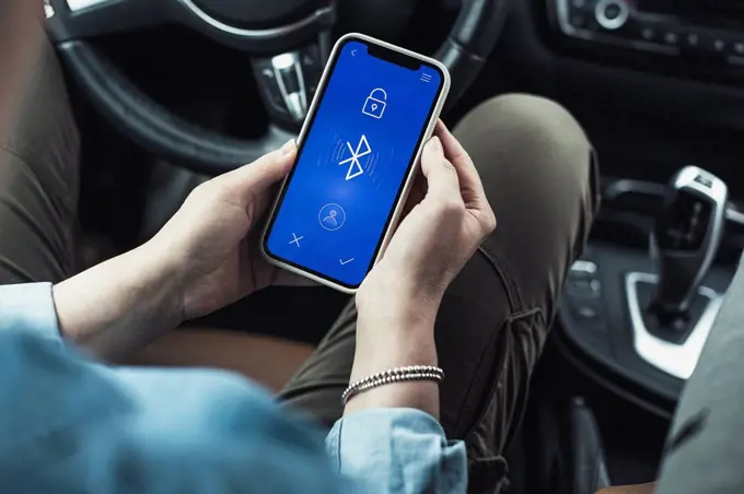 Woman accessing bluetooth on mobile phone in car