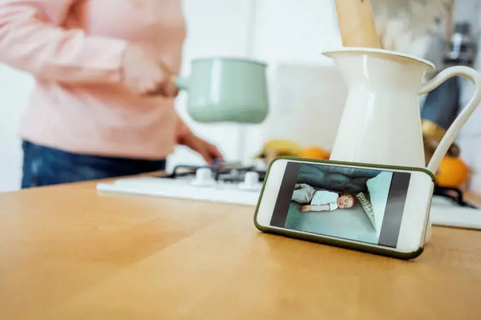 Woman preparing food during video call through mobile phone at kitchen