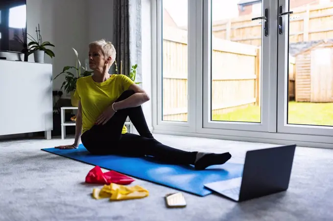 Woman stretching on mat while exercising at home