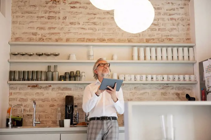 Businessman controlling pendant light through digital tablet in cafeteria