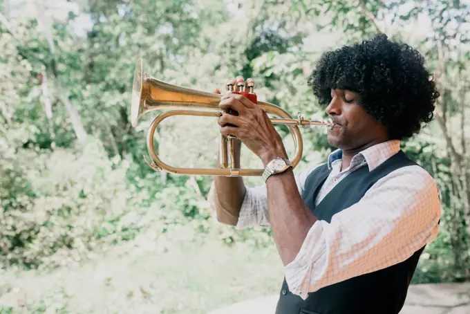 Man with curly black hair practicing trumpet