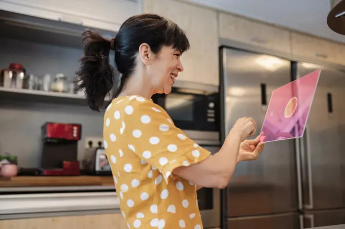 Happy woman using digital tablet in kitchen at home