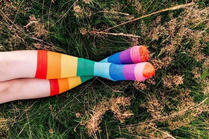 Woman wearing rainbow socks with legs crossed at ankle on grass