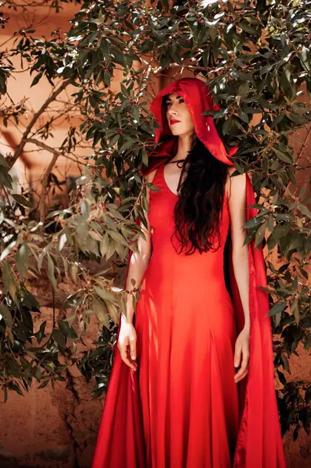 Woman in little red riding hood costume amidst plants