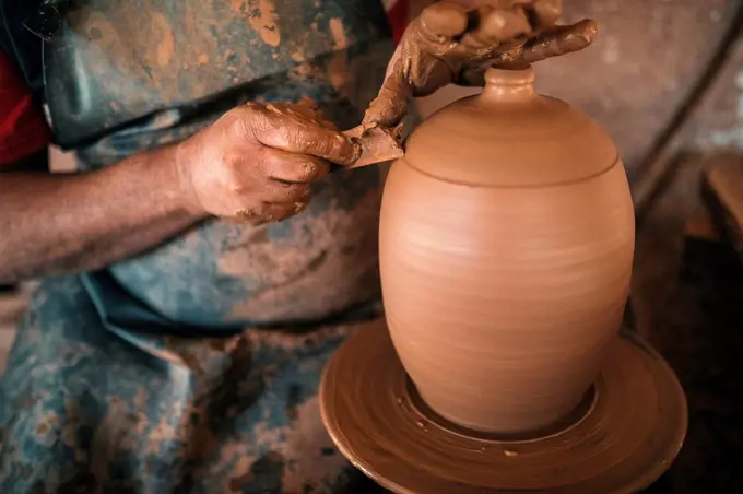 Potter making lid of pot in workshop