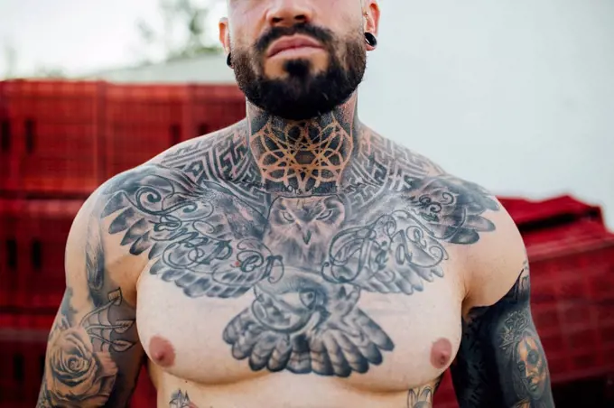 Shirtless hipster man with tattoo on neck and chest