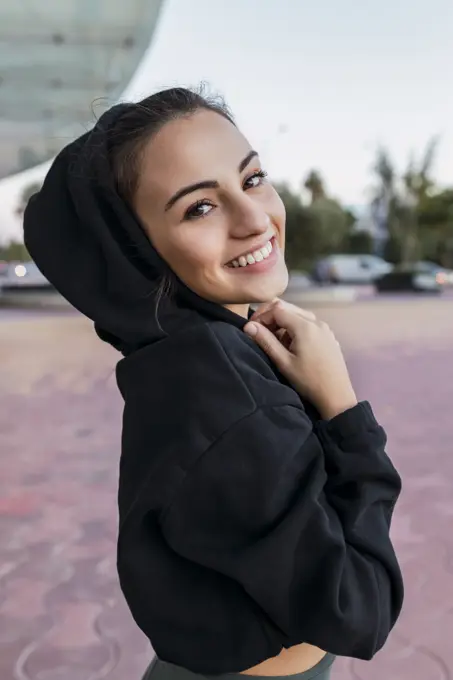 Smiling sportswoman wearing hoodie in park