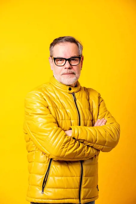 Confident man with arms crossed against yellow background