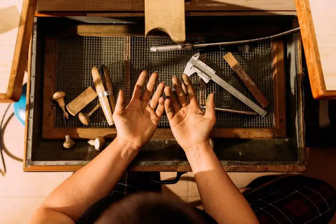 Dirty hands of female craftsperson in front of work tools at workshop