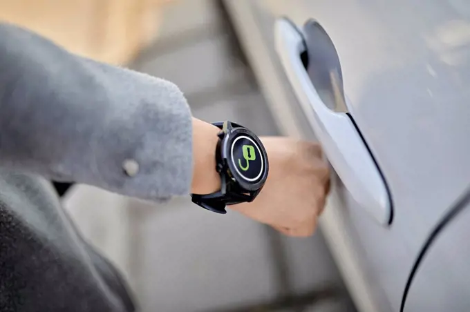 Woman unlocking car door with smart wristwatch