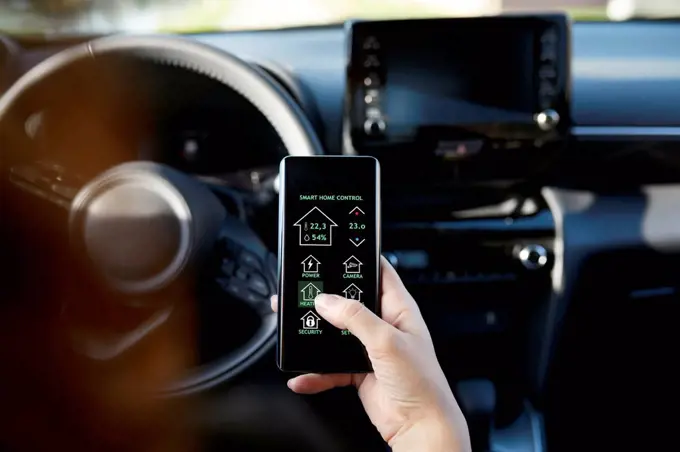 Businesswoman controlling smart house through mobile phone in car