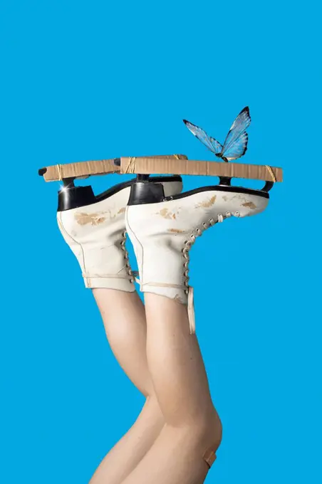 Butterfly on ice skate of teenage girl against blue background