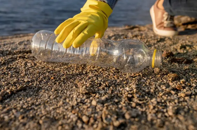 Volunteer wearing glove picking up plastic bottle