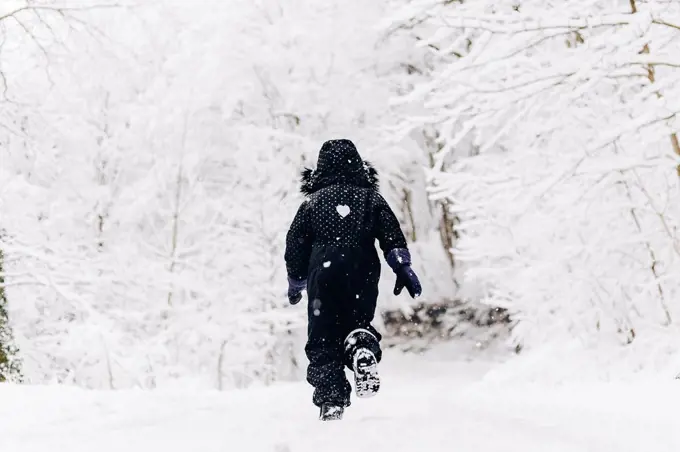 Girl running in snowy winter forest