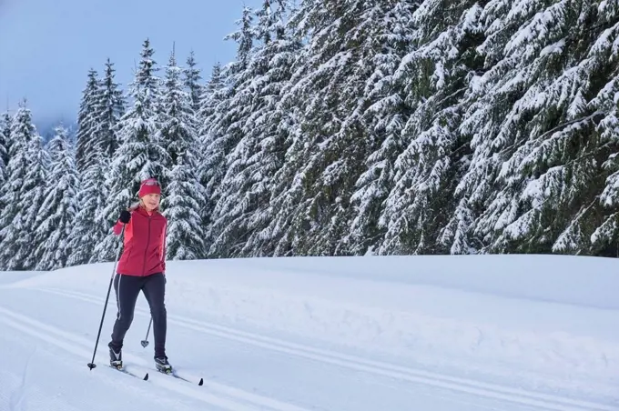 Senior woman skiing in winter forest