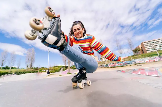 Smiling woman roller skating in skateboard park on sunny day
