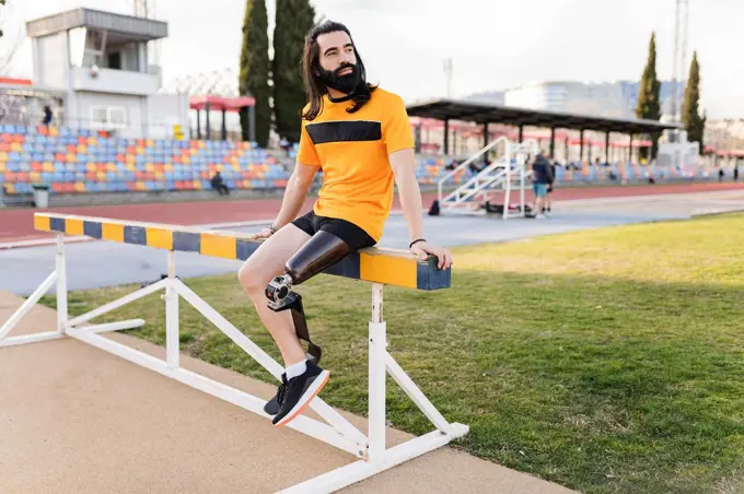 Man with prosthetic leg sitting on hurdle