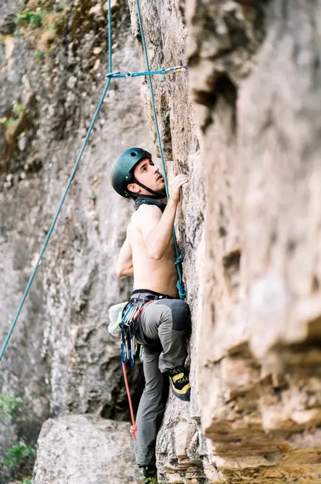 Shirtless man climbing on rock at weekend