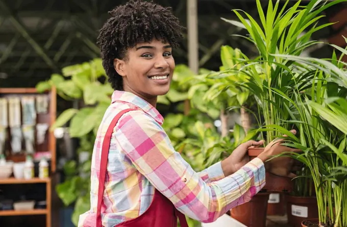 Happy gardener holding potted plant at nursery