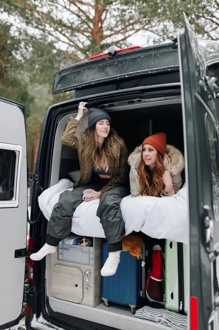 Woman talking with friend lying in campervan