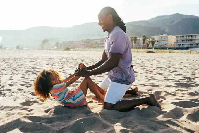Father playing with daughter at beach