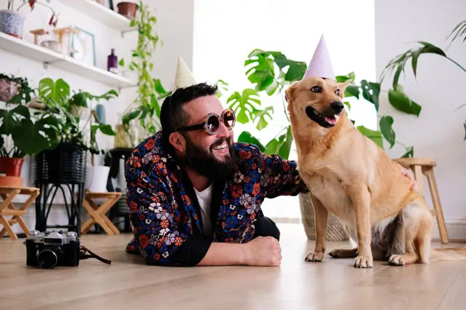 Happy man wearing sunglasses lying by pet dog at home