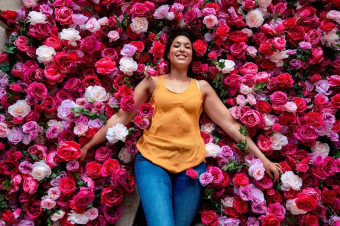 Smiling woman lying on rose flowers