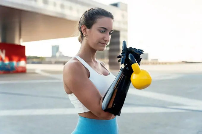 Young woman with arm prosthesis exercising with kettlebell