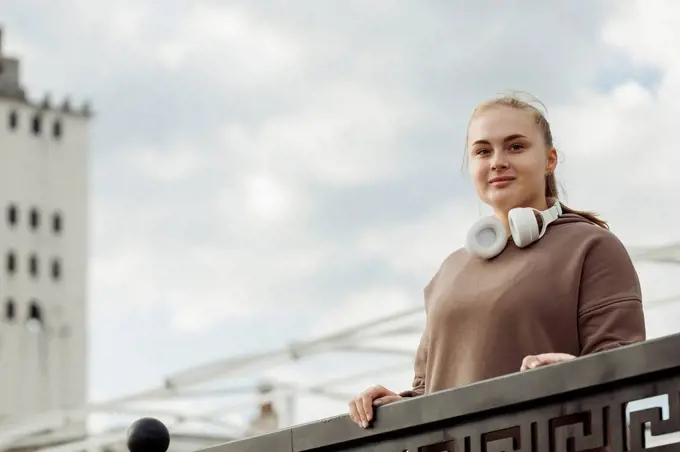 Smiling young woman standing by railing