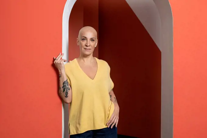 Confident bald woman with hand on hip at doorway